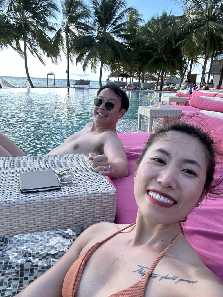 Couple unwinding by the pool in a luxurious Maldives resort, Ozen Life Maadhoo