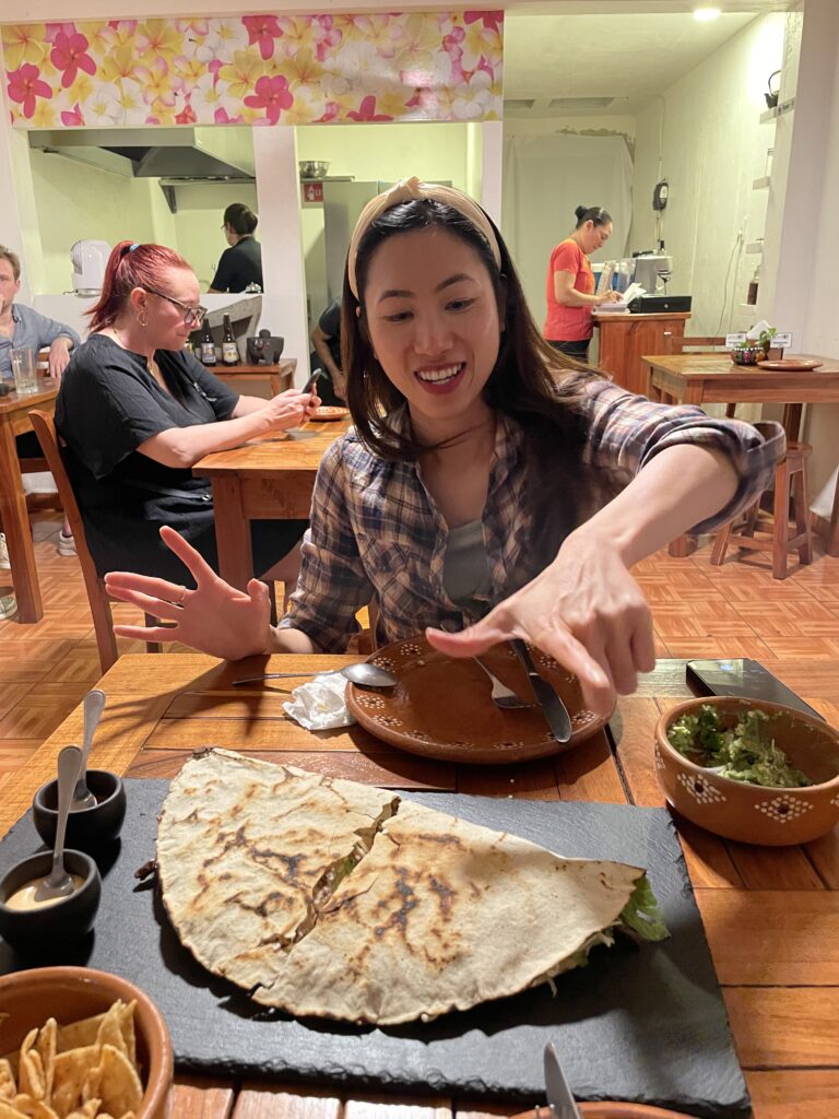 Savoring a giant tlayuda at Casa Oaxaca Antojitos in Valladolid – Oaxacan street food at its finest with cheese, meats, and fresh veggies.
