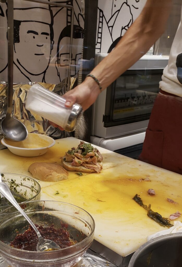 Florentine street vendor preparing a lampredotto sandwich at a local food stall