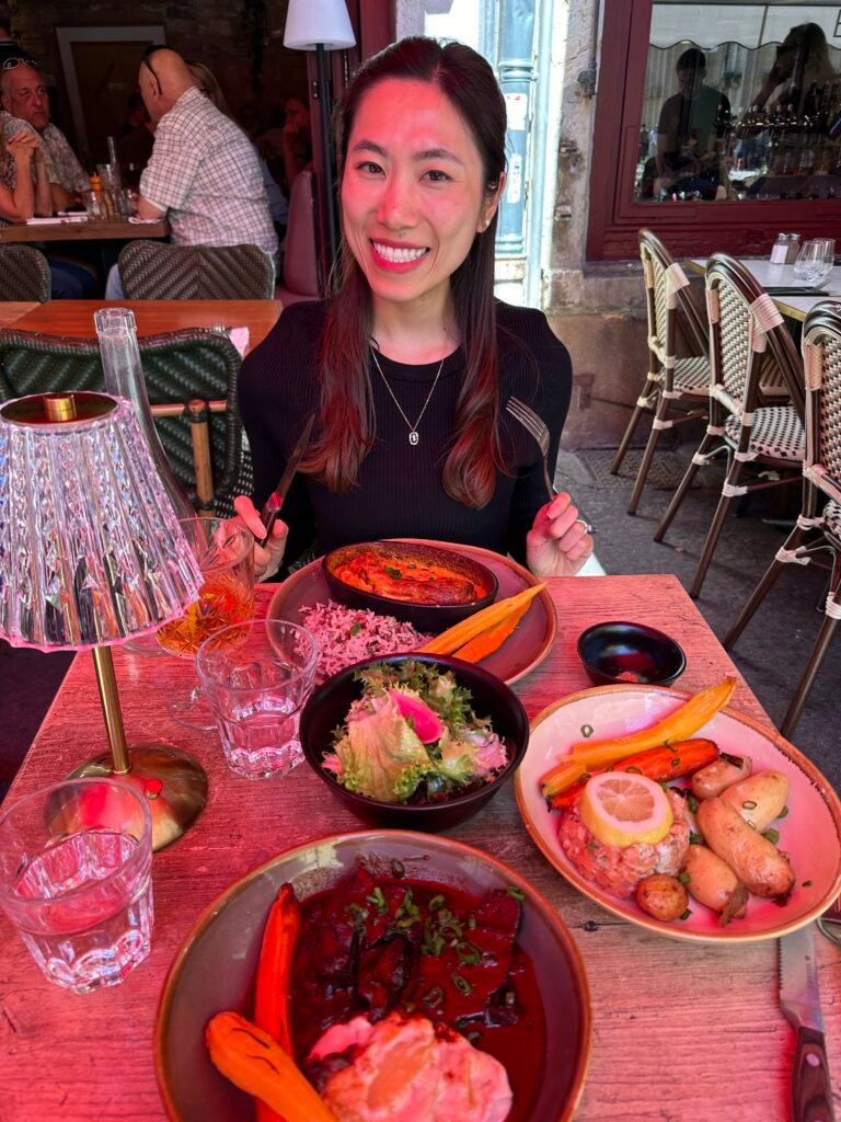 Outdoor dining experience at a quaint bouchon in Lyon's historic old town, with customers enjoying classic French dishes under umbrellas.