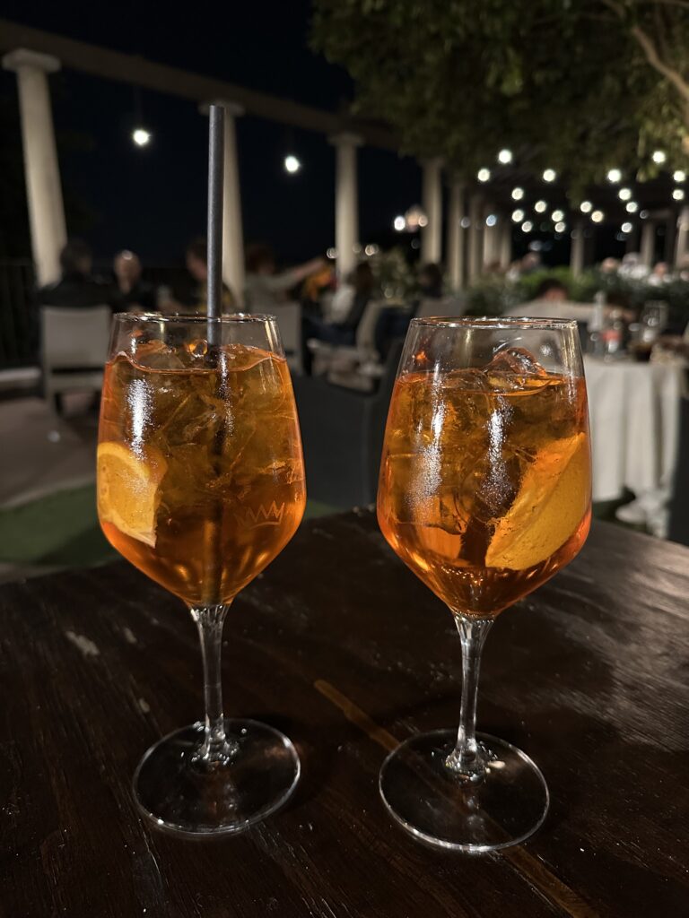 Enjoying Aperol Spritz with a scenic overlook from Castel San Pietro showing the Adige River winding through Verona