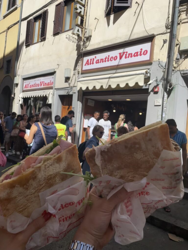 Hands holding a stuffed Florentine sandwich from All’Antico Vinaio in the streets of Florence