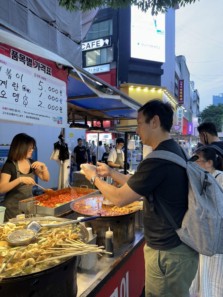 Myeongdong Night Market in Seoul with bustling crowds and colourful street food stalls serving popular Korean snacks