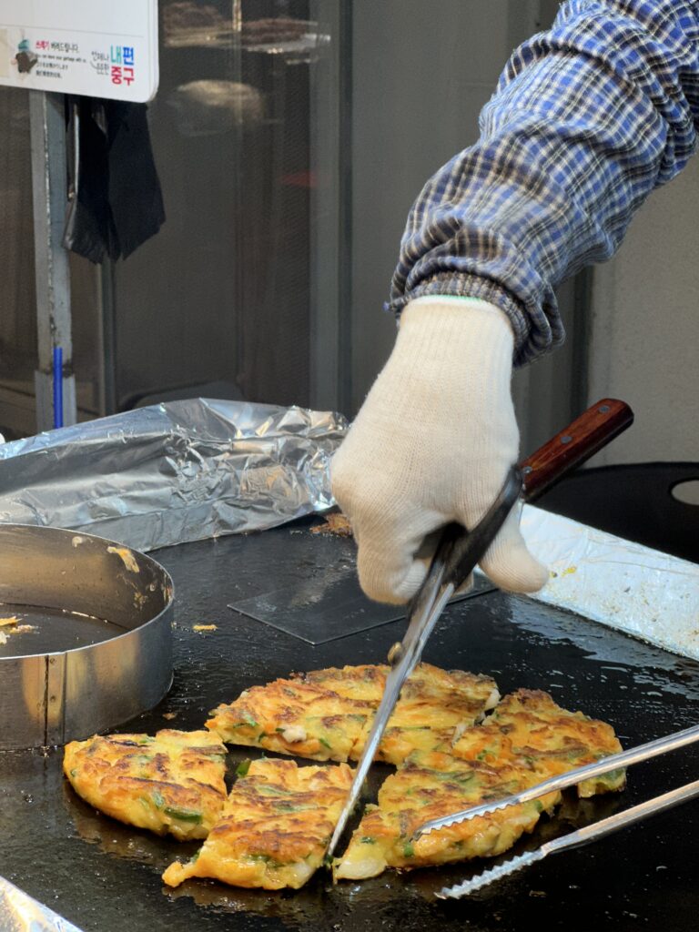 Night scene at Myeongdong Market featuring sizzling Korean street food vendors and a lively atmosphere