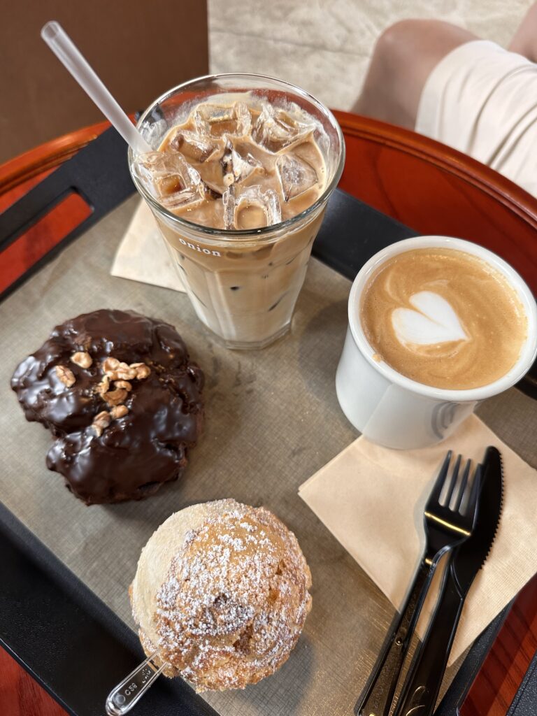 A variety of pastries and freshly made coffee displayed on a wooden table at Onion Bakery