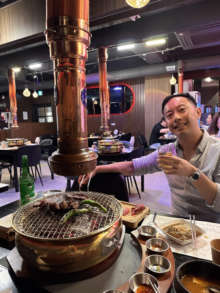 Grilling assorted marinated meats on a Korean BBQ grill at a bustling Seoul restaurant