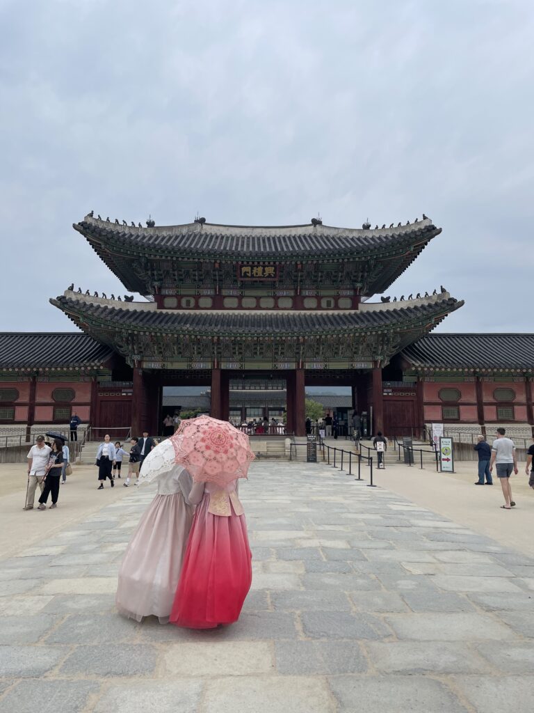 Visitors wearing colorful hanboks walking through Gyeongbokgung Palace courtyard.