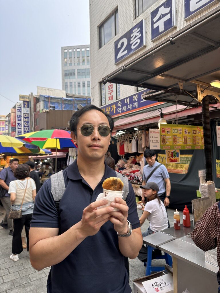 Tourist tasting three varieties of hotteok, Korean sweet pancakes, at Namdaemun market in Seoul
