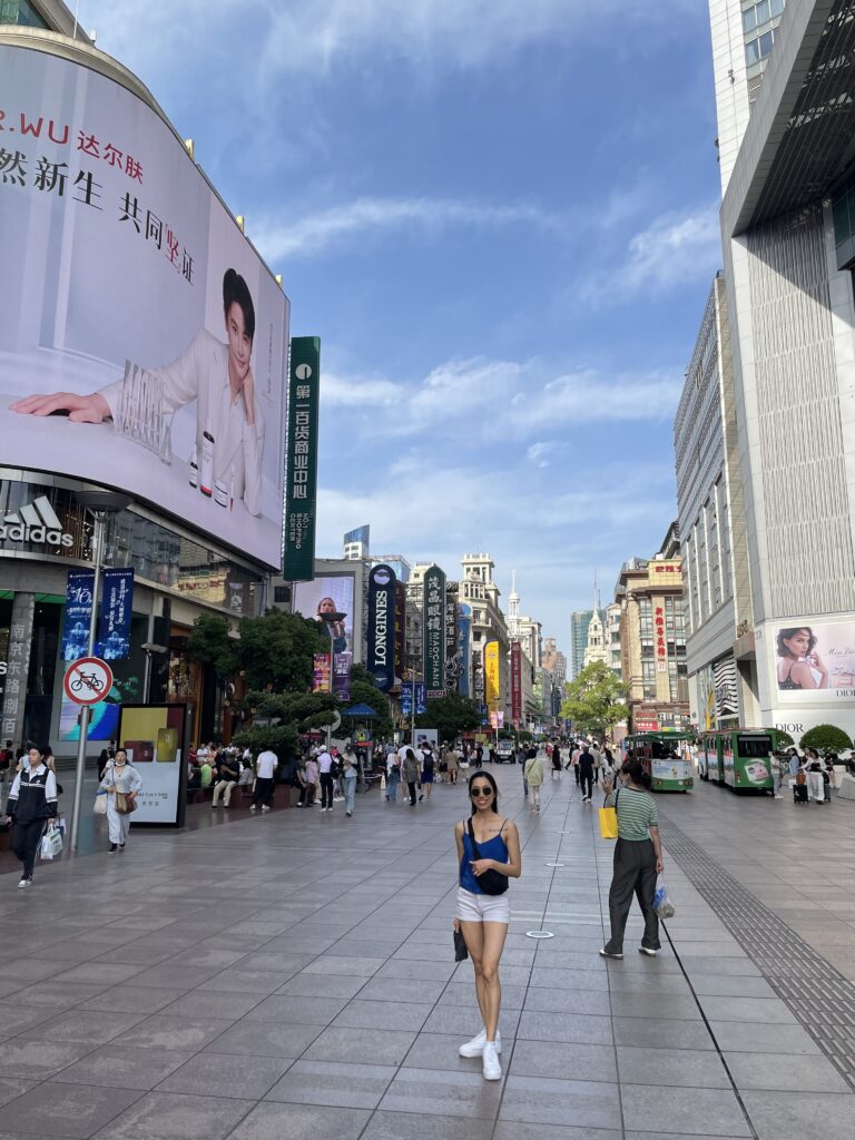 Iconic Nanjing Road shopping street in Shanghai filled with people, luxury shops, and colorful signage
