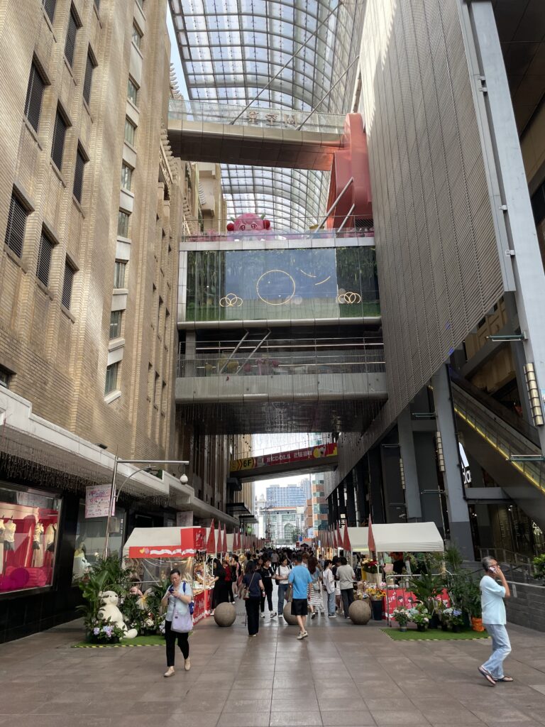Daytime view of Nanjing Road in Shanghai with shoppers, street performers, and towering storefronts