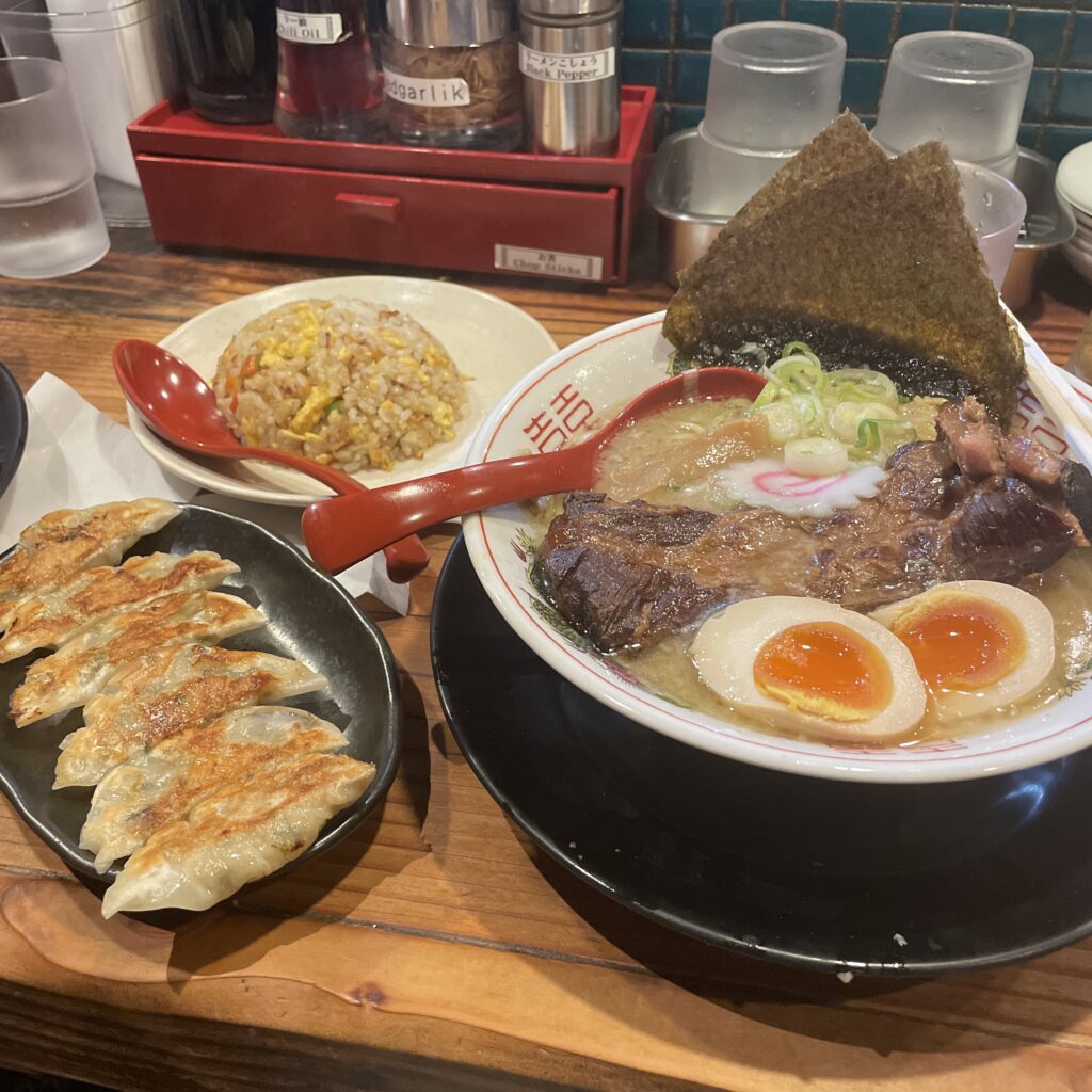 A hearty bowl of pork rib ramen at Hanamaruken Hozenji, with tender ribs resting on springy noodles in savory broth, garnished with green onions and bamboo shoots.