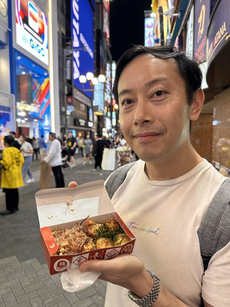 Trying freshly made takoyaki street food in bustling Dotonbori Osaka