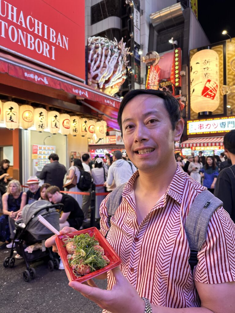 Freshly cooked takoyaki topped with sauce, mayo, and bonito flakes, served hot at a street food stall in Dotonbori, Osaka.