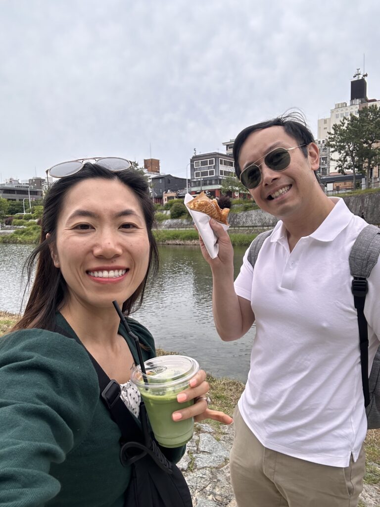 Couple enjoying taiyaki and matcha latte while strolling along the river in Kyoto, traditional Japanese treats by the scenic waterways
