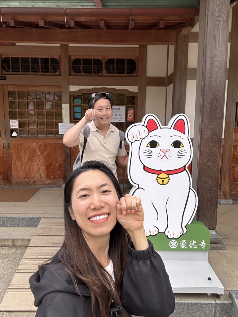 Couple posing with giant beckoning cat statue at Gotokuji Temple Tokyo
