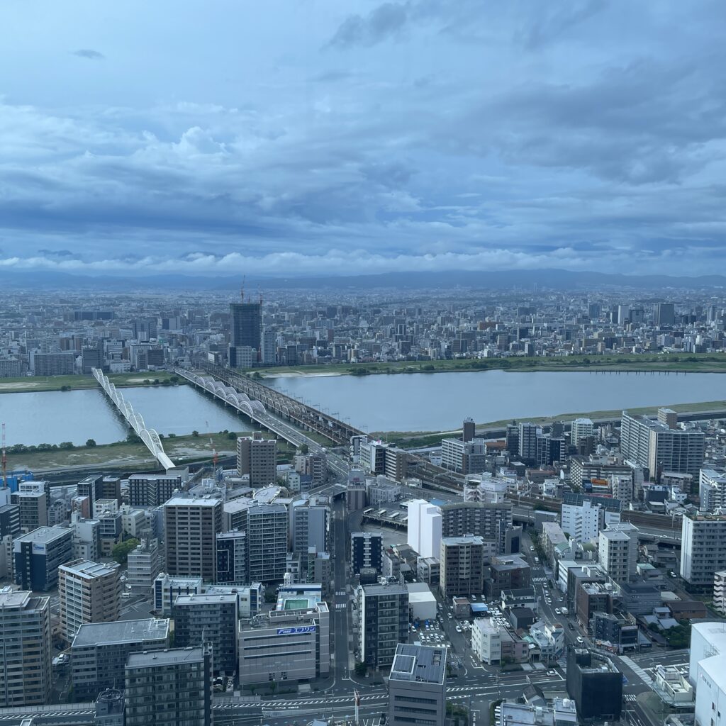 The iconic Umeda Sky Building, with twin towers linked by a futuristic sky bridge and rooftop garden, standing against the Osaka skyline.