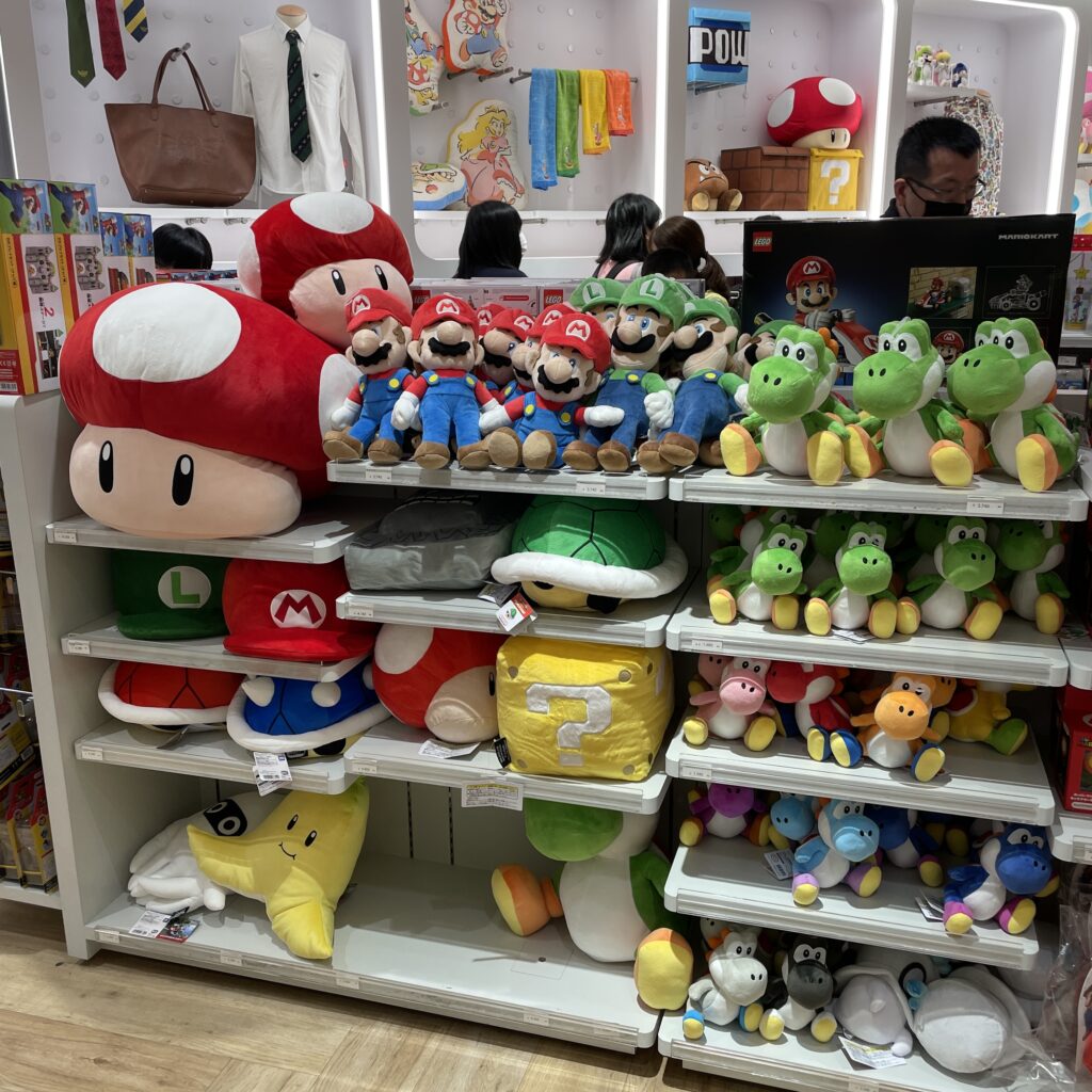 The Nintendo Store in Osaka, with life-sized character statues, vibrant wall art, and crowds of shoppers taking photos.