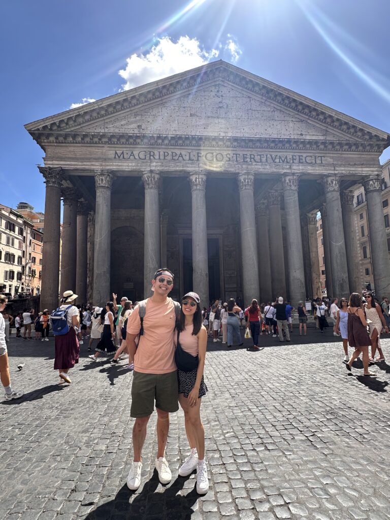 Exterior of the Pantheon in Rome with grand granite columns and busy piazza.
