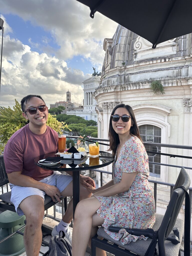 Guests enjoying drinks at Oro Bistrot rooftop terrace overlooking Rome rooftops.
