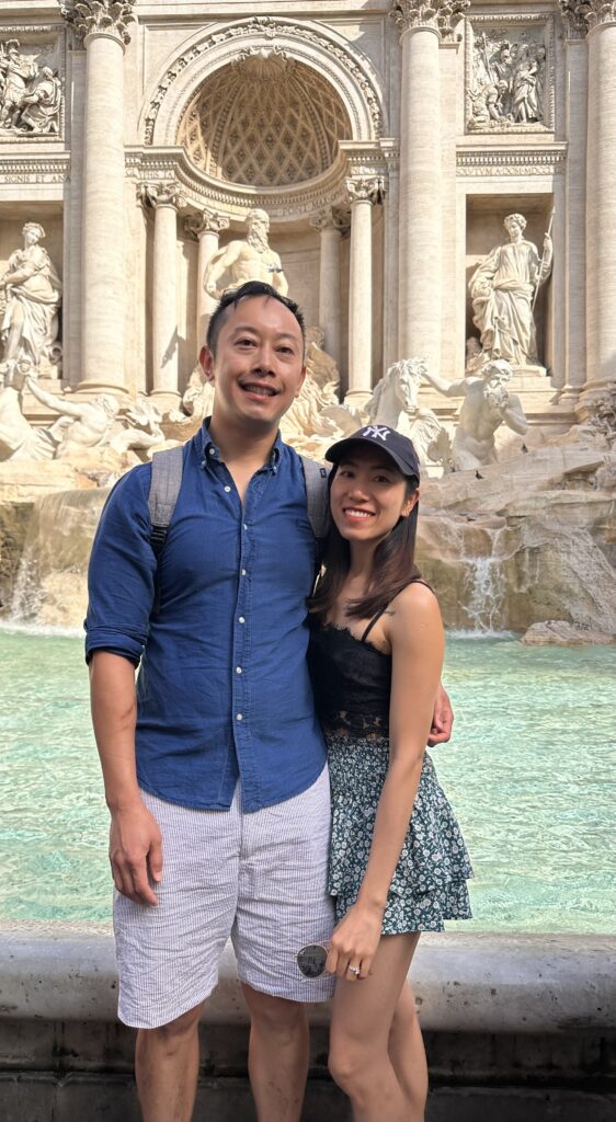Visitors taking photos near the Trevi Fountain on a sunny day in Rome.