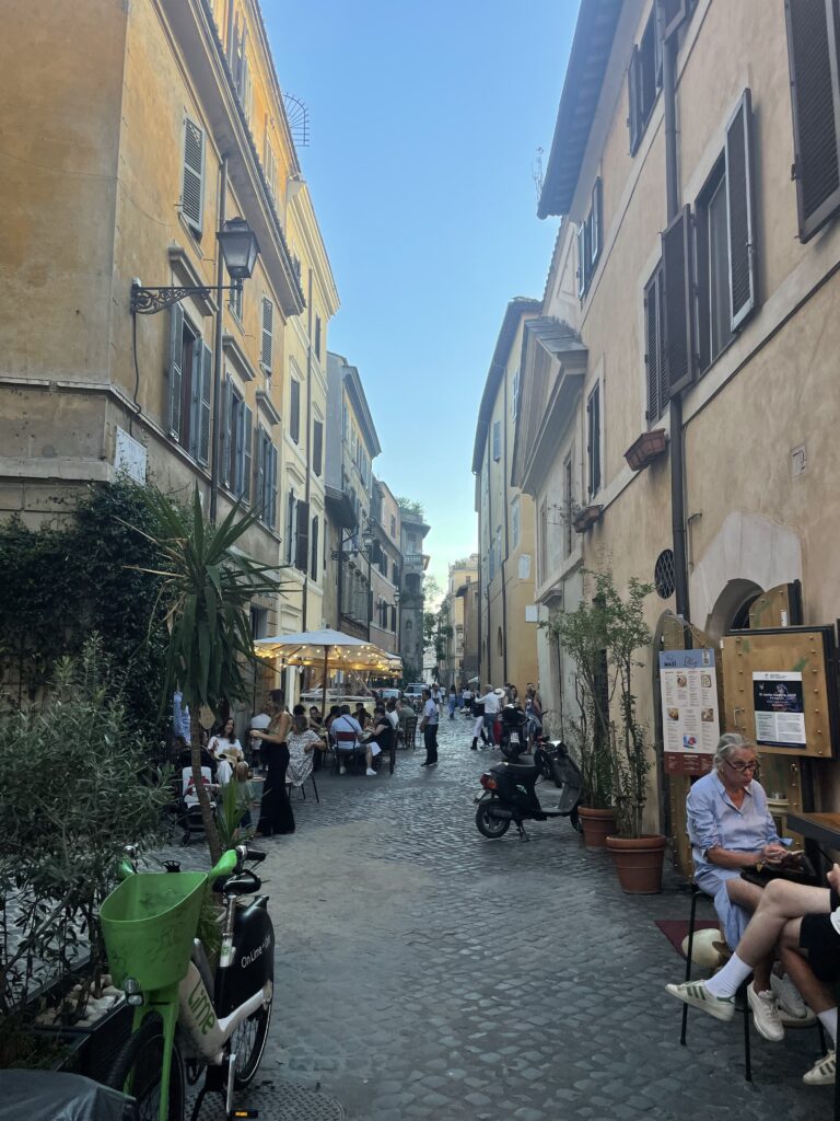 People dining al fresco on Trastevere’s charming cobbled streets.